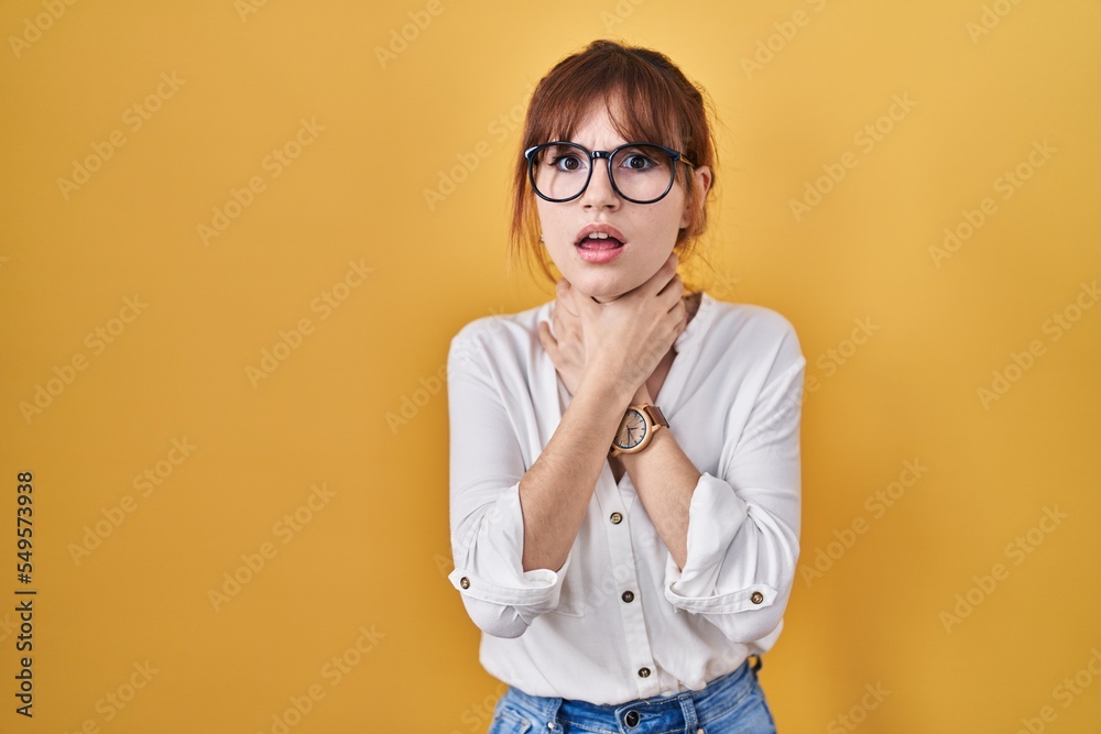 Young beautiful woman wearing casual shirt over yellow background shouting suffocate because painful strangle. health problem. asphyxiate and suicide concept.