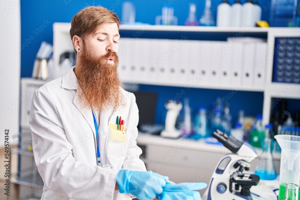 Young redhead man scientist wearing gloves at laboratory