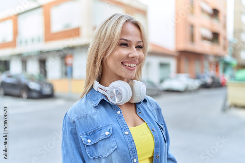 Young blonde woman smiling confident wearing headphones at street