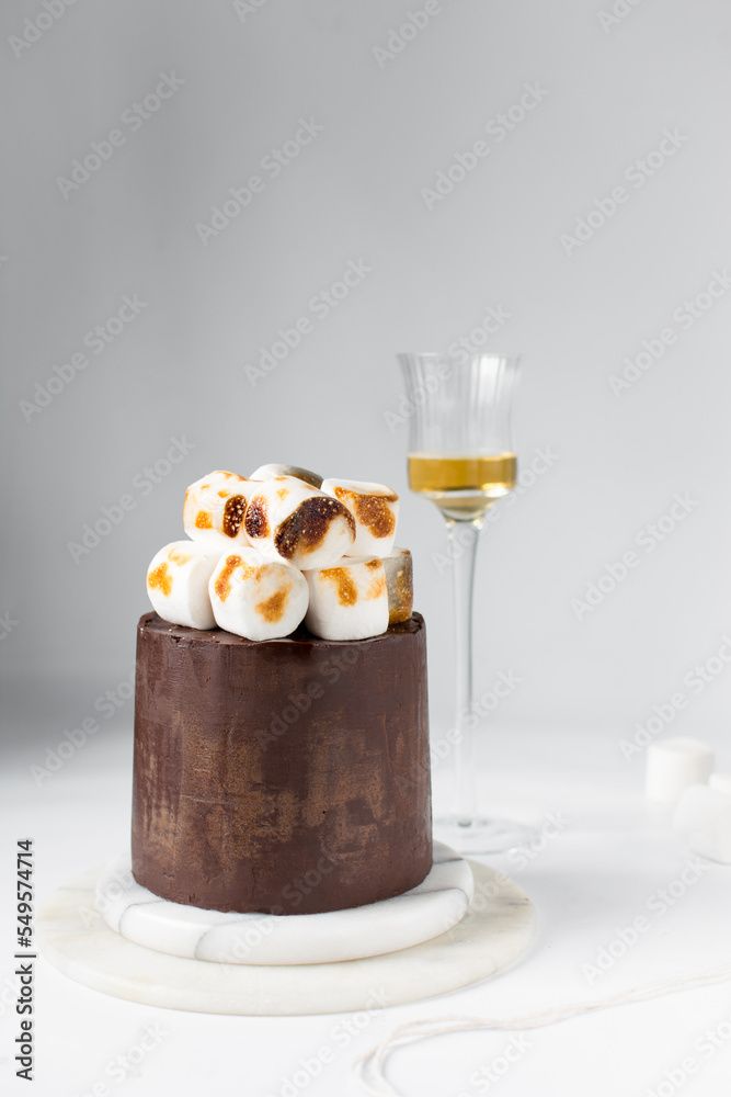 Toasted marshmallows on a ganache covered chocolate cake, hot chocolate cake, cake on a marble plate Toasted marshmallows on a ganache covered chocolate cake, hot chocolate cake, cake on a marble plate