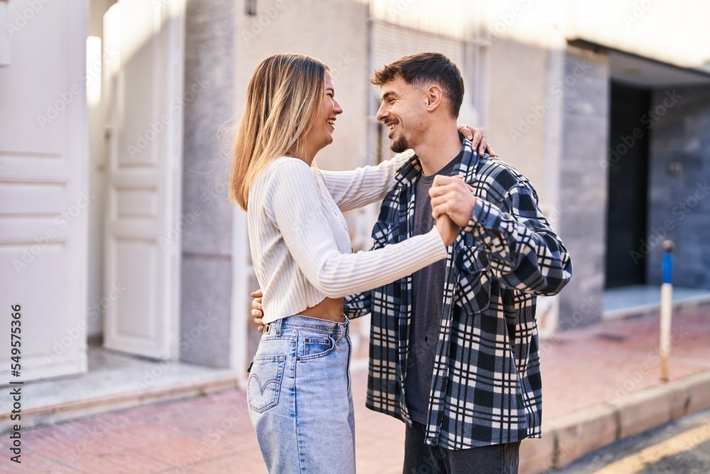 Naklejka premium Young man and woman couple smiling confident dancing at street