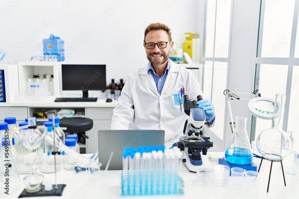 Middle age hispanic man wearing scientist uniform working at laboratory Middle age hispanic man wearing scientist uniform working at laboratory