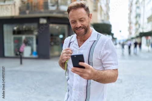Middle age man smiling confident using smartphone at street
