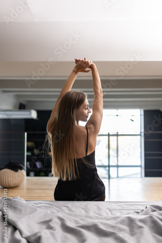 Back view of woman stretching arms after wake up in the morning