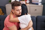 Man and woman couple hugging each other sitting on sofa at home