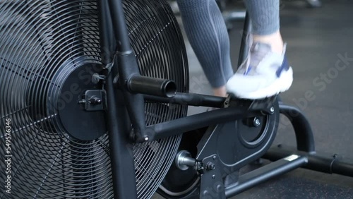 Close-up of a girl's legs pedaling while exercising on a bicycle in the gym. Cardio training  photo