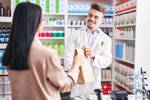 Man and woman pharmacist and client holding shopping bag at pharmacy