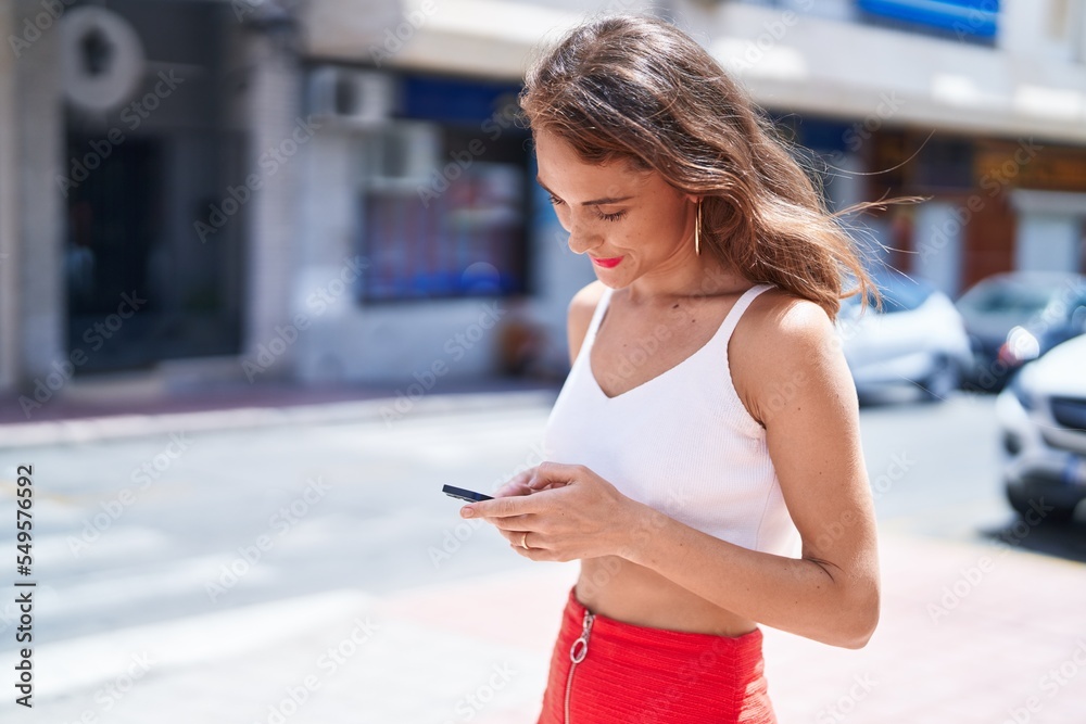 Young beautiful hispanic woman using smartphone with serious expression at street