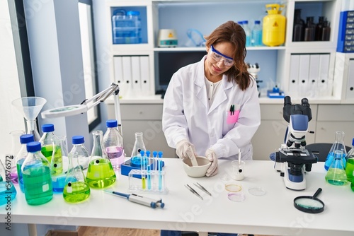 Young latin woman wearing scientist uniform working at laboratory