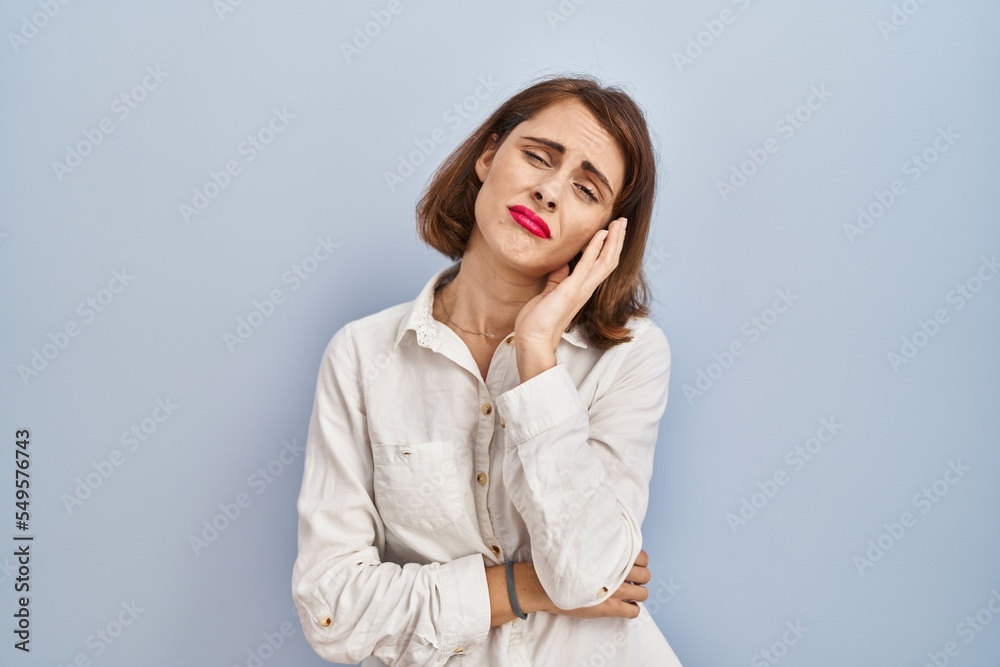 Young beautiful woman standing casual over blue background thinking looking tired and bored with depression problems with crossed arms. Young beautiful woman standing casual over blue background thinking looking tired and bored with depression problems with crossed arms.