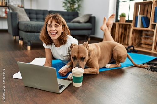Young caucasian woman sportswoman smiling confident using laptop with dog at home
