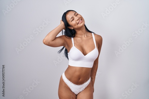 Hispanic woman wearing lingerie smiling confident touching hair with hand up gesture, posing attractive and fashionable © Krakenimages.com