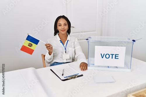Young african american woman smiling confident holding moldova flag working at electoral college photo