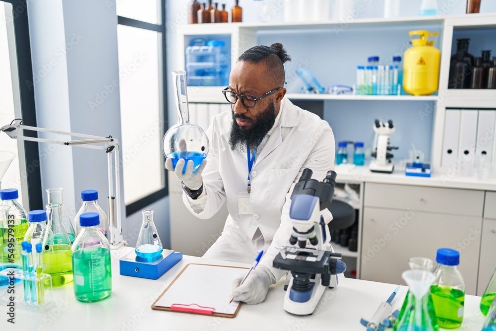 Young african american man wearing scientist uniform holding test tube at laboratory