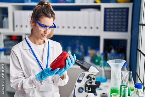 Young woman scientist holding pepper at laboratory