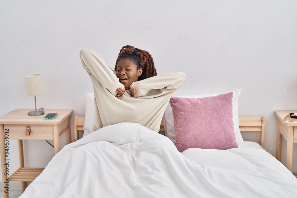 African american woman waking up stretching arms at bedroom