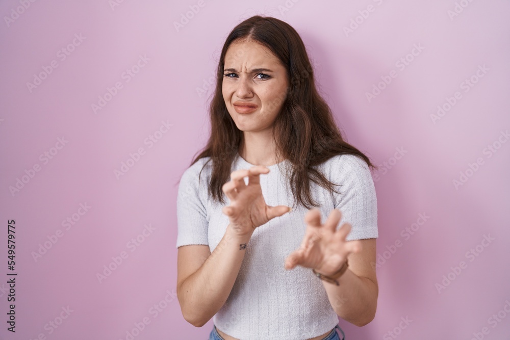 Young hispanic girl standing over pink background disgusted expression, displeased and fearful doing disgust face because aversion reaction. Young hispanic girl standing over pink background disgusted expression, displeased and fearful doing disgust face because aversion reaction.