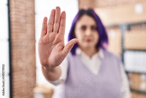 Young beautiful plus size woman ecommerce business worker doing stop gesture with hand at office