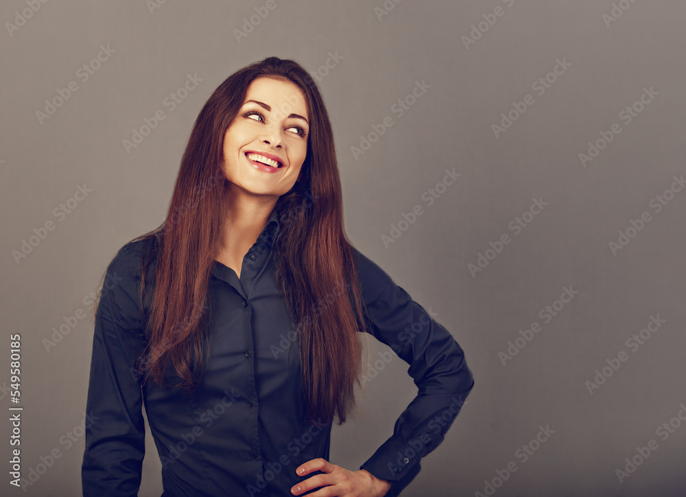 Beautiful confident thinking toothy smiling business woman in blue formal shirt looking on grey background with empty copy space for text. Closeup Beautiful confident thinking toothy smiling business woman in blue formal shirt looking on grey background with empty copy space for text. Closeup