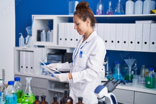 Young woman scientist reading document working at laboratory