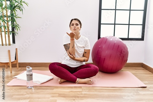 Young hispanic woman training at sport center looking at the camera blowing a kiss with hand on air being lovely and sexy. love expression.