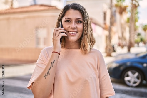 Young hispanic woman smiling confident talking on the smartphone at street