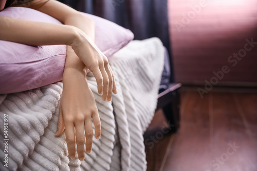 Hands of young woman lying on pillow in bedroom, closeup