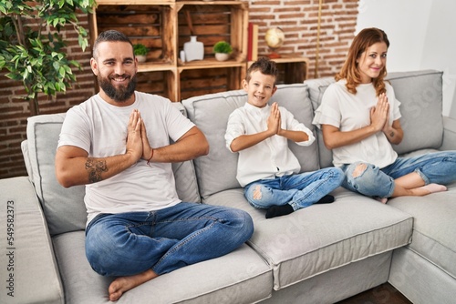 Fototapeta Naklejka Na Ścianę i Meble -  Family doing yoga exercise sitting on sofa at home