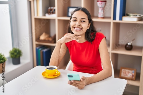 Young african american woman using smartphone drinking coffee at home