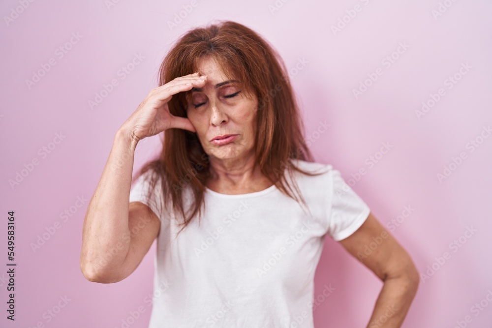 Middle age woman standing over pink background worried and stressed about a problem with hand on forehead, nervous and anxious for crisis Middle age woman standing over pink background worried and stressed about a problem with hand on forehead, nervous and anxious for crisis