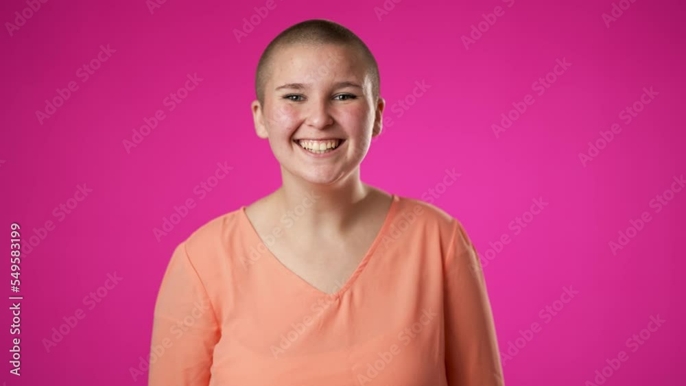 Portrait of happy gender fluid non binary young woman 20s smiling waving inviting isolated on pink background. Portrait of happy gender fluid non binary young woman 20s smiling waving inviting isolated on pink background.