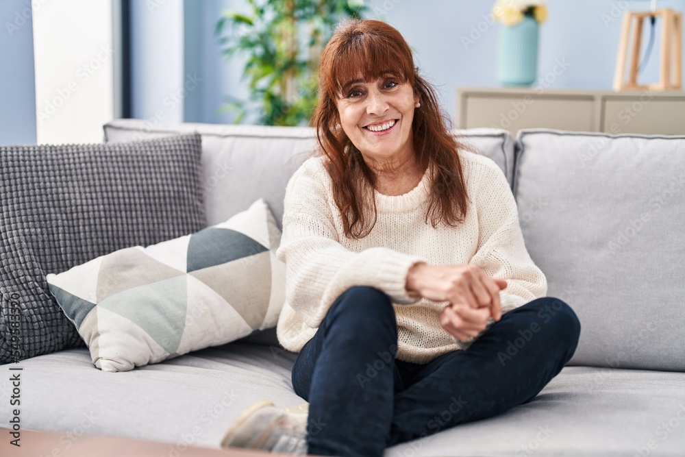 Middle age woman smiling confident sitting on sofa at home Middle age woman smiling confident sitting on sofa at home