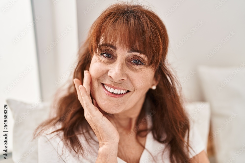 Middle age woman smiling confident sitting on bed at bedroom Middle age woman smiling confident sitting on bed at bedroom