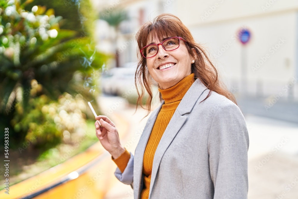 Middle age woman business executive smoking cigarette at park