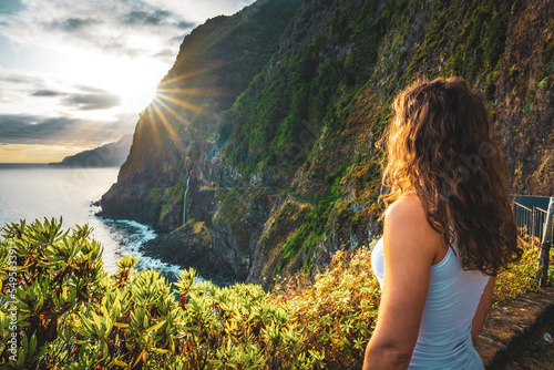 Sporty woman looking at waterfall flowing into the sea in atmospheric morning atmosphere. Viewpoint Véu da Noiva, Madeira Island, Portugal, Europe. photo