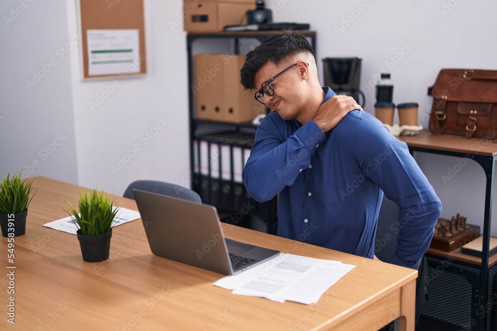 Young hispanic man business worker suffering for backache working at office Young hispanic man business worker suffering for backache working at office