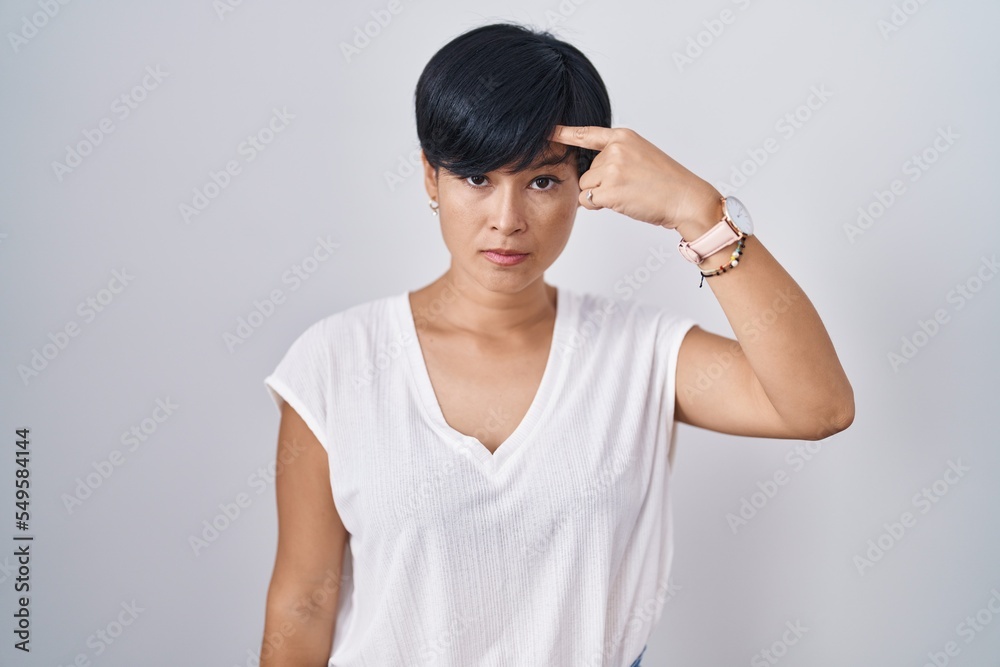 Young asian woman with short hair standing over isolated background pointing unhappy to pimple on forehead, ugly infection of blackhead. acne and skin problem Young asian woman with short hair standing over isolated background pointing unhappy to pimple on forehead, ugly infection of blackhead. acne and skin problem