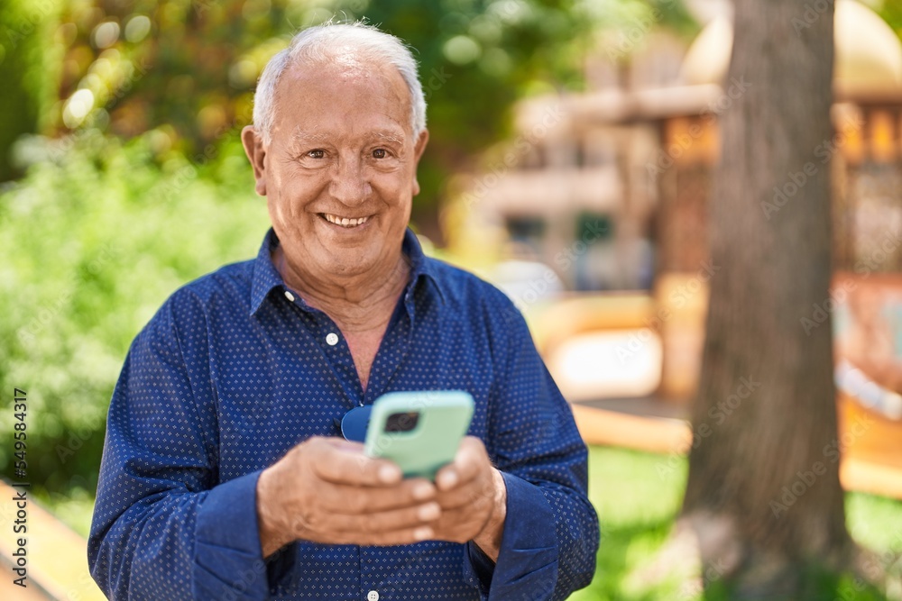 Senior grey-haired man smiling confident using smartphone at park Senior grey-haired man smiling confident using smartphone at park