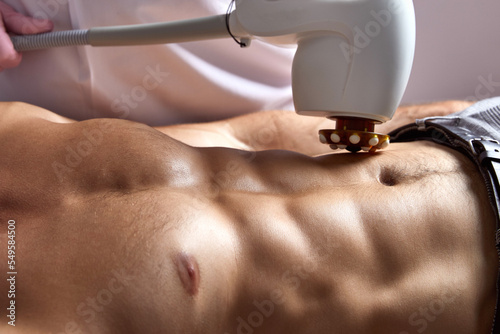 Man receiving fat reductive skin lifting body treatment on modern equipment at cosmetology clinic photo