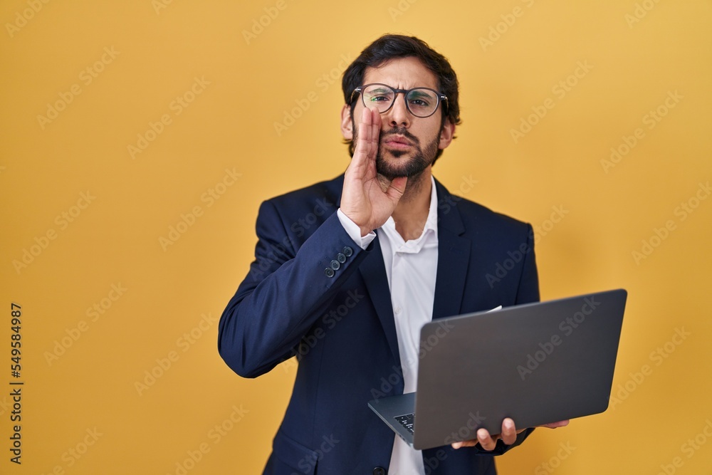 Handsome latin man working using computer laptop hand on mouth telling secret rumor, whispering malicious talk conversation Handsome latin man working using computer laptop hand on mouth telling secret rumor, whispering malicious talk conversation