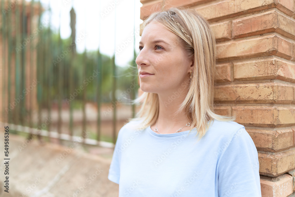Fototapeta premium Young blonde woman looking to the side with serious expression at street