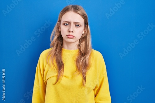 Young caucasian woman standing over blue background depressed and worry for distress, crying angry and afraid. sad expression.