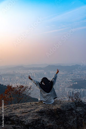 A woman who sits on a rock at the top of the mountain in front of Daegu and enjoys the autumn mood