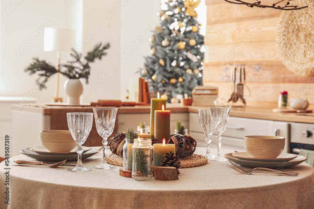 Christmas table setting with burning candles and wreath in kitchen Christmas table setting with burning candles and wreath in kitchen