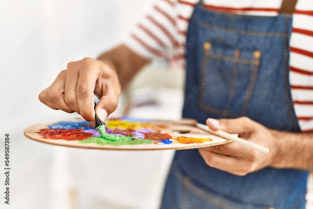 Young hispanic man mixing color on palette at art studio Young hispanic man mixing color on palette at art studio