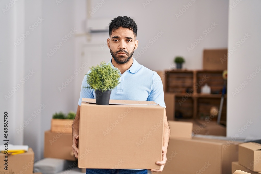 Hispanic man with beard moving to a new home holding box depressed and worry for distress, crying angry and afraid. sad expression. Hispanic man with beard moving to a new home holding box depressed and worry for distress, crying angry and afraid. sad expression.
