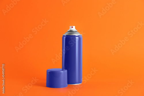 Blue can of spray paint on orange background. Space for text