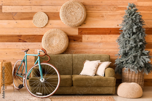 Interior of living room with bicycle, green sofa and Christmas tree