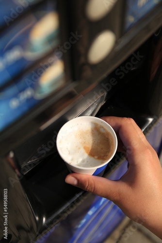 Quadro su tela Woman taking paper cup with coffee from vending machine, above view