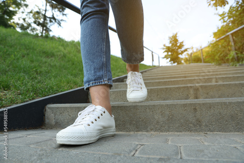 Woman in stylish black sneakers walking down stairs, closeup